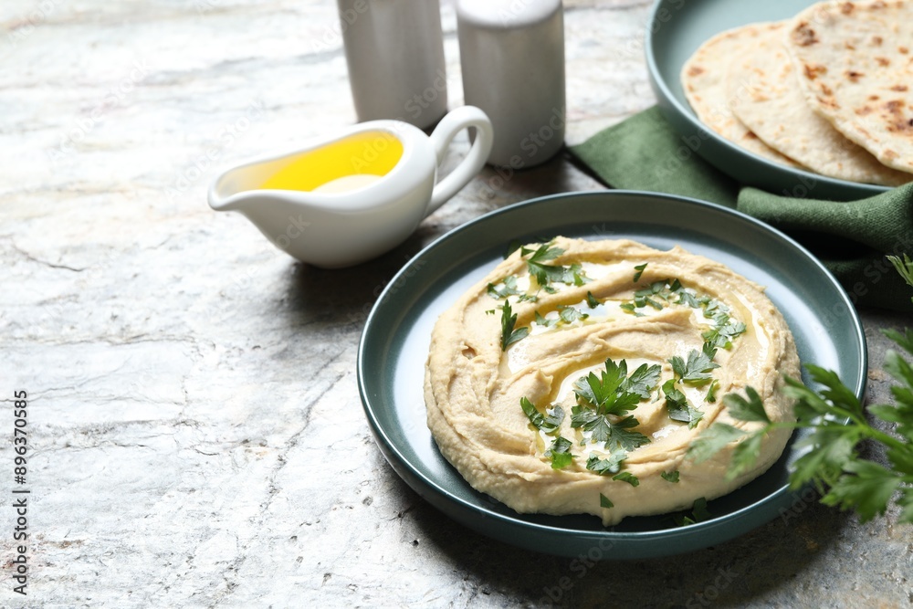 Delicious hummus with olive oil and parsley on grey textured table, space for text Delicious hummus with olive oil and parsley on grey textured table, space for text