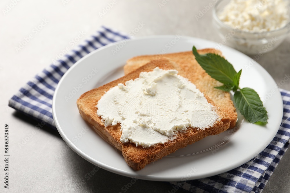 Delicious toasted bread slices with cream cheese and mint on grey table Delicious toasted bread slices with cream cheese and mint on grey table
