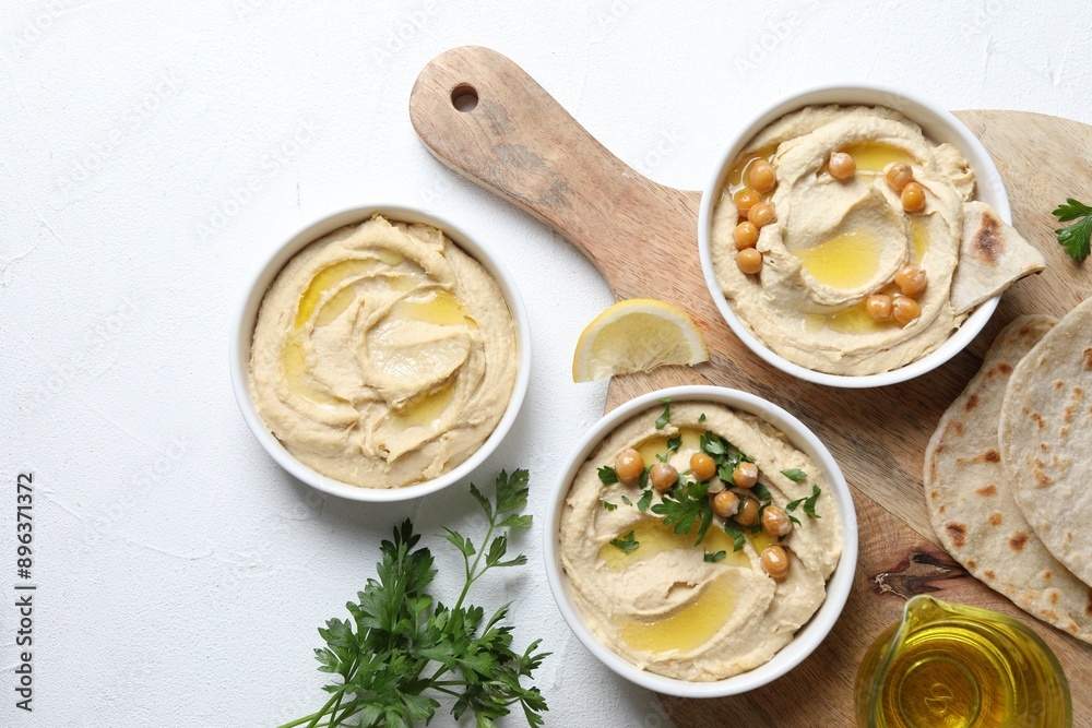 Delicious hummus with olive oil and chickpeas served on white table, flat lay Delicious hummus with olive oil and chickpeas served on white table, flat lay
