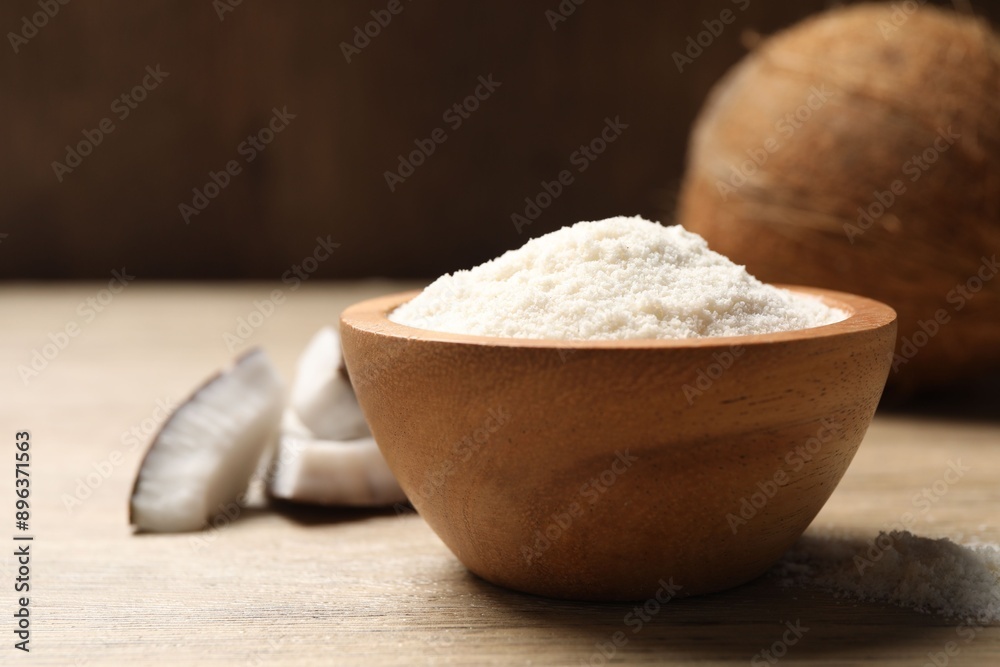 Fresh coconut flour in bowl and nut on wooden table Fresh coconut flour in bowl and nut on wooden table