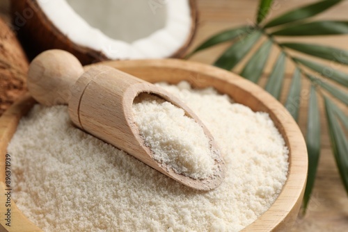 Coconut flour in bowl and scoop on table, closeup