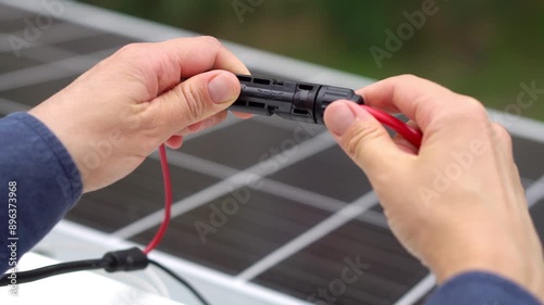 Close up footage  of technician's hands connecting mc4 connectors over the solar panel.