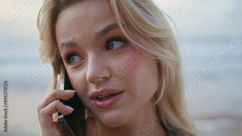 Pretty blonde talking mobile phone at ocean shore. Closeup beautiful woman face