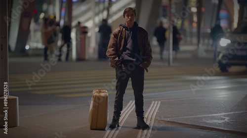 Wallpaper Mural A man standing in a city night scene with a suitcase, either waiting or planning his next journey Torontodigital.ca