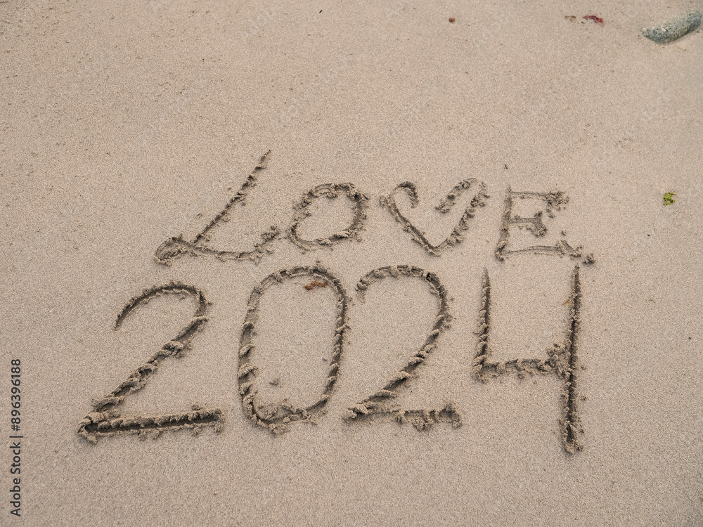 Fototapeta premium Sign love and 2024 on a sand of a beach.