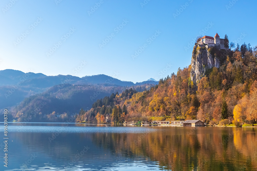 Naklejka premium Castle of Bled on the rock in autumn time in sunny day blue sky