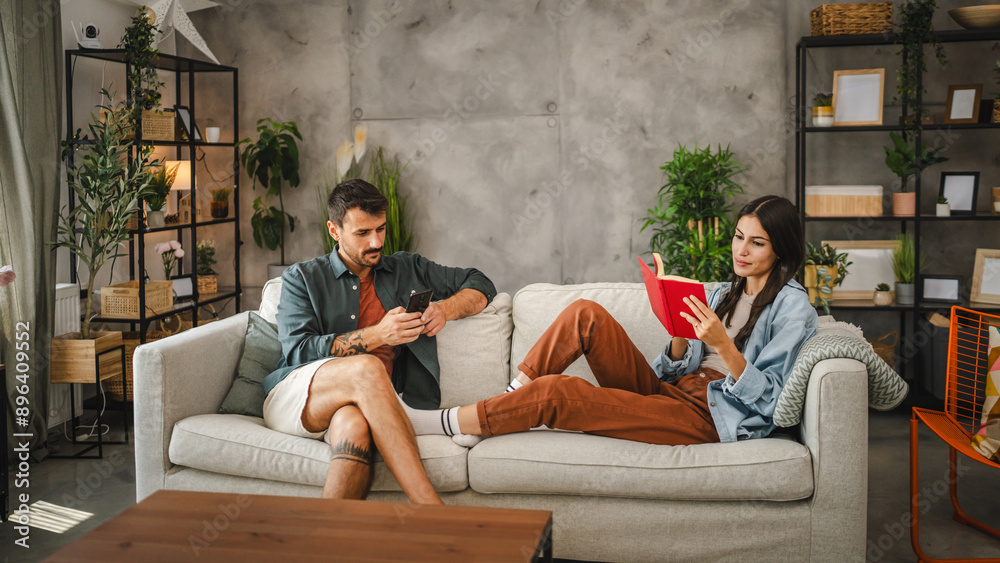 Obraz premium relaxed couple girlfriend read a book and boyfriend use mobile phone