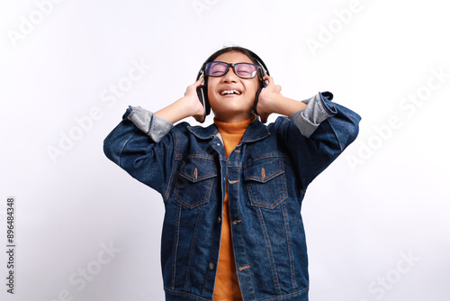 Portrait of beautiful little girl wearing a glasses while listening music with headphones