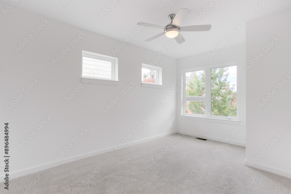 Fototapeta premium Minimalist White Room With Modern Ceiling Fan And Ample Natural Light