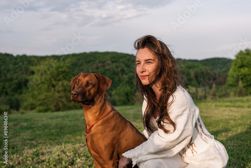 young beautiful female playing with her dog outside in the backyard with a gorgeous hill view
