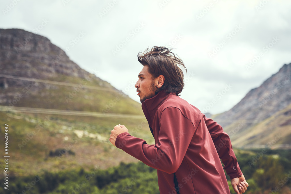 Naklejka premium Man, outdoor and running on mountain for fitness, endurance training and personal challenge for wellness. Male person, side view and space in nature for trail adventure, hiking workout and exercise.