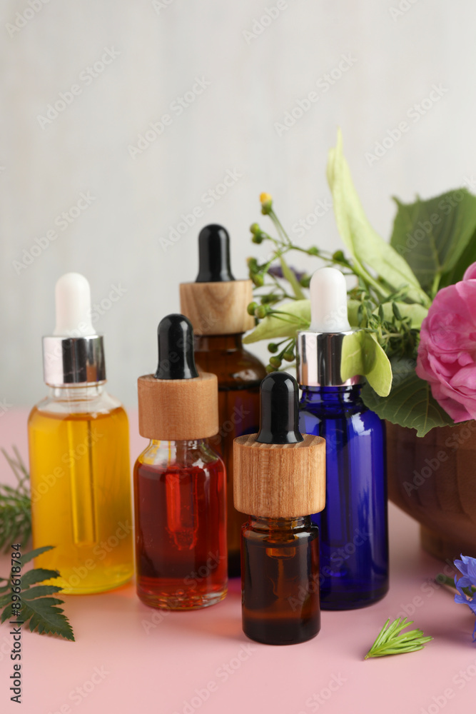 Aromatherapy. Different essential oils and flowers on pink table Aromatherapy. Different essential oils and flowers on pink table