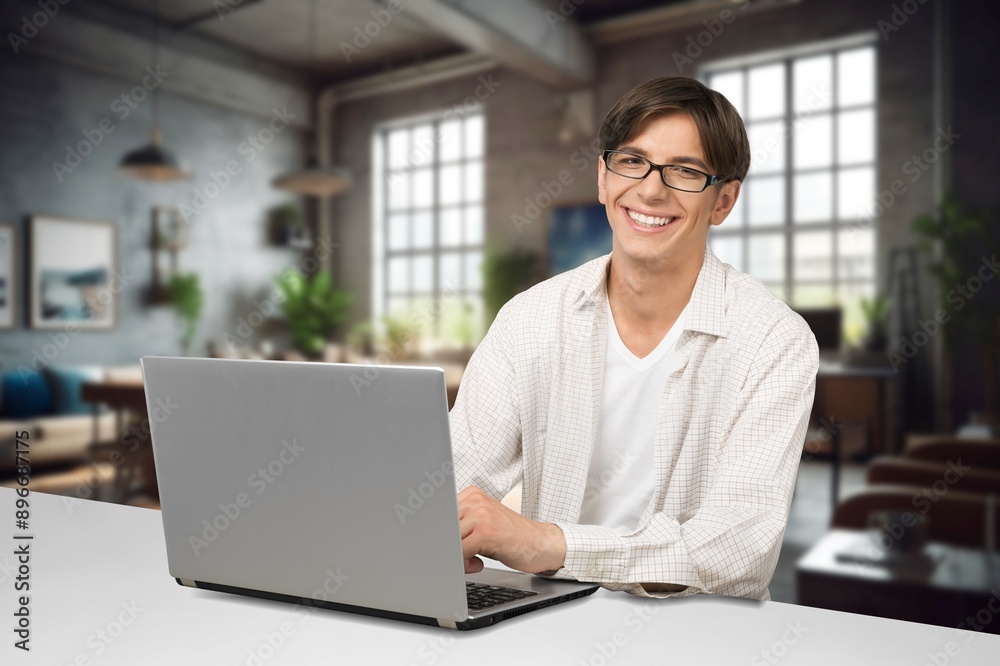 A cheerful male worker answering client typing on laptop A cheerful male worker answering client typing on laptop