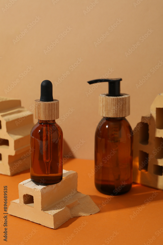 Cosmetic bottles and bricks on orange background Cosmetic bottles and bricks on orange background