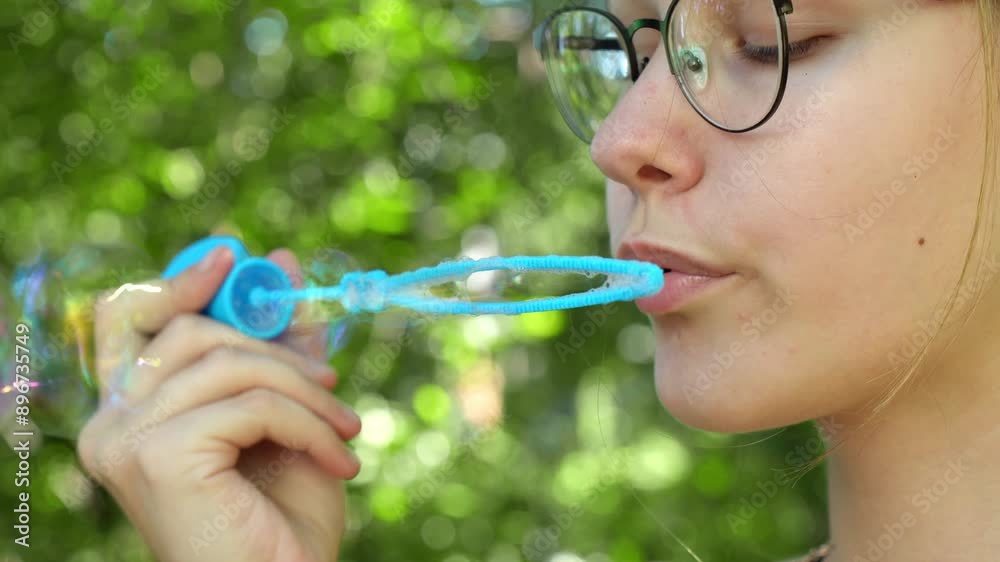 Young girl excitedly releases shimmering soap bubbles into the air in nature. Young girl excitedly releases shimmering soap bubbles into the air in nature.
