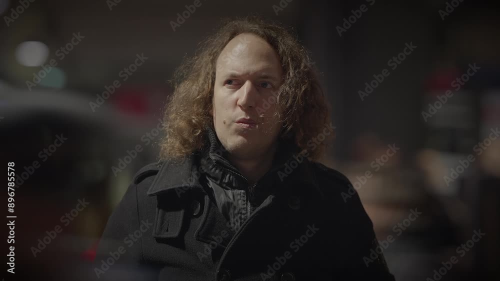 A man with curly hair in a city night scene surrounded by lights and blurred background A man with curly hair in a city night scene surrounded by lights and blurred background