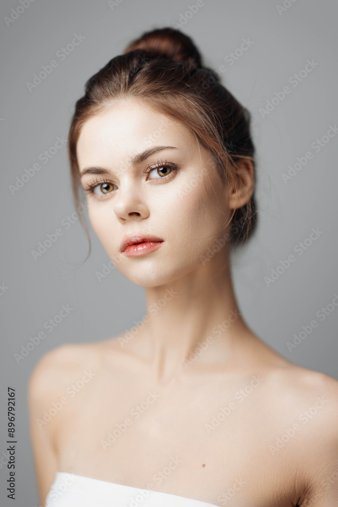 Beautiful young woman with a white towel posing in a studio on a grey background Beautiful young woman with a white towel posing in a studio on a grey background