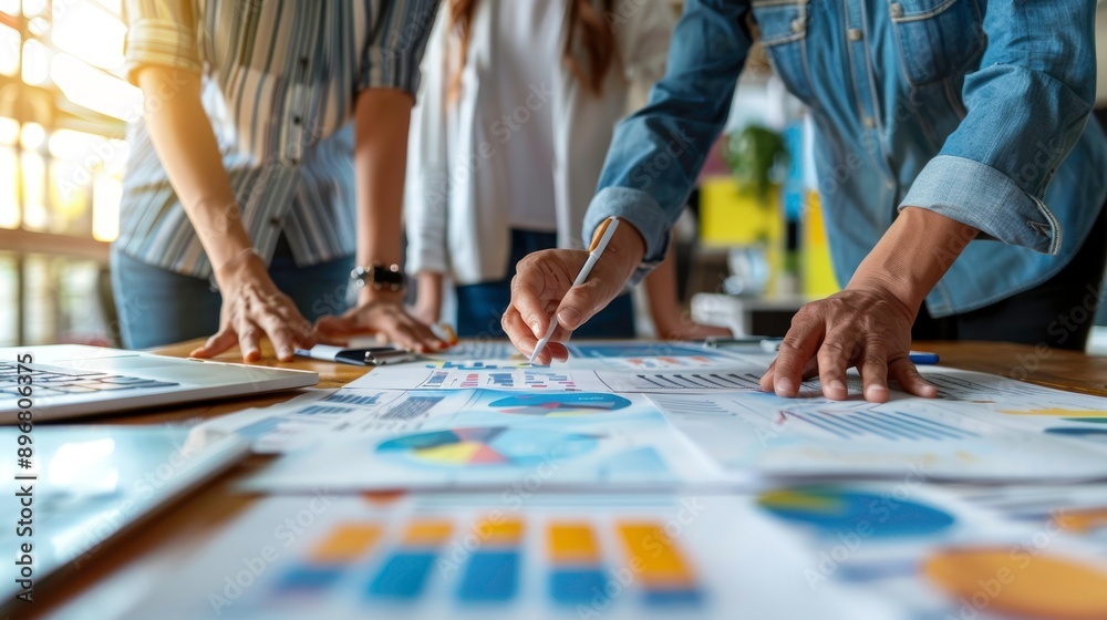 Fototapeta premium Team collaborates on project analysis using charts and graphs for effective decision-making in a modern workspace.