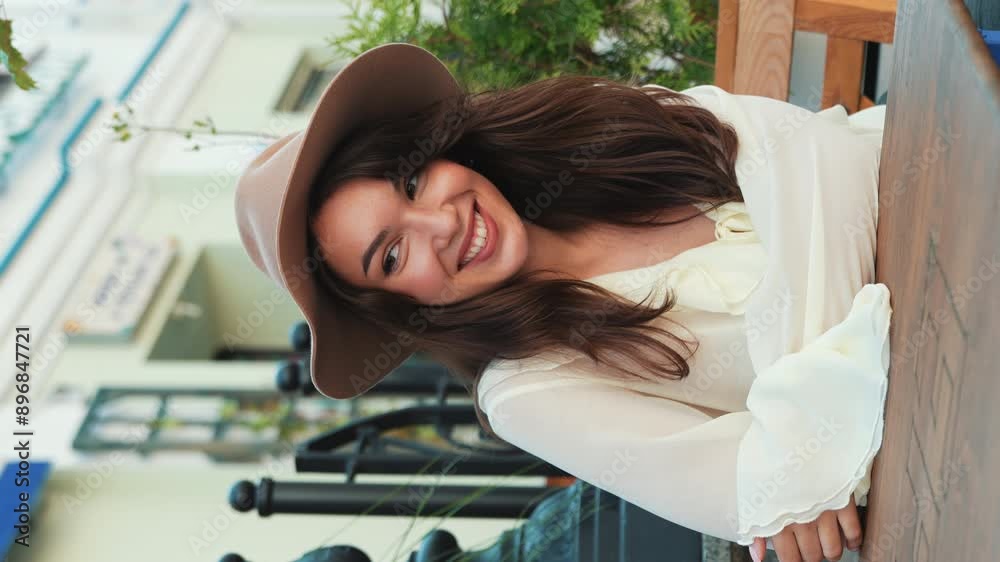 Young beautiful smiling hipster woman in trendy summer white blouse. Carefree woman posing in the street in cafe. Positive model outdoors. Cheerful and happy. At coffee shop. Vertical video Young beautiful smiling hipster woman in trendy summer white blouse. Carefree woman posing in the street in cafe. Positive model outdoors. Cheerful and happy. At coffee shop. Vertical video