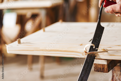 Carpenter working wood plank using hand plane in workshop