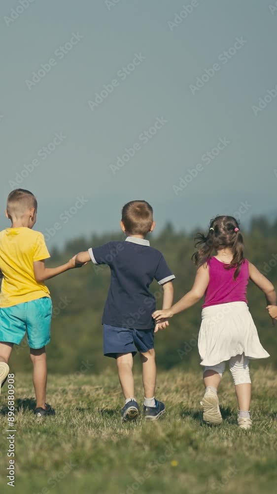 Vertical Screen: Caucasian Children Running with Backs Turned. They Hold Hands and Raise Them at the Same Time to Celebrate the Finishing of the Race. Concept of Fun, Teamwork, Togetherness Vertical Screen: Caucasian Children Running with Backs Turned. They Hold Hands and Raise Them at the Same Time to Celebrate the Finishing of the Race. Concept of Fun, Teamwork, Togetherness