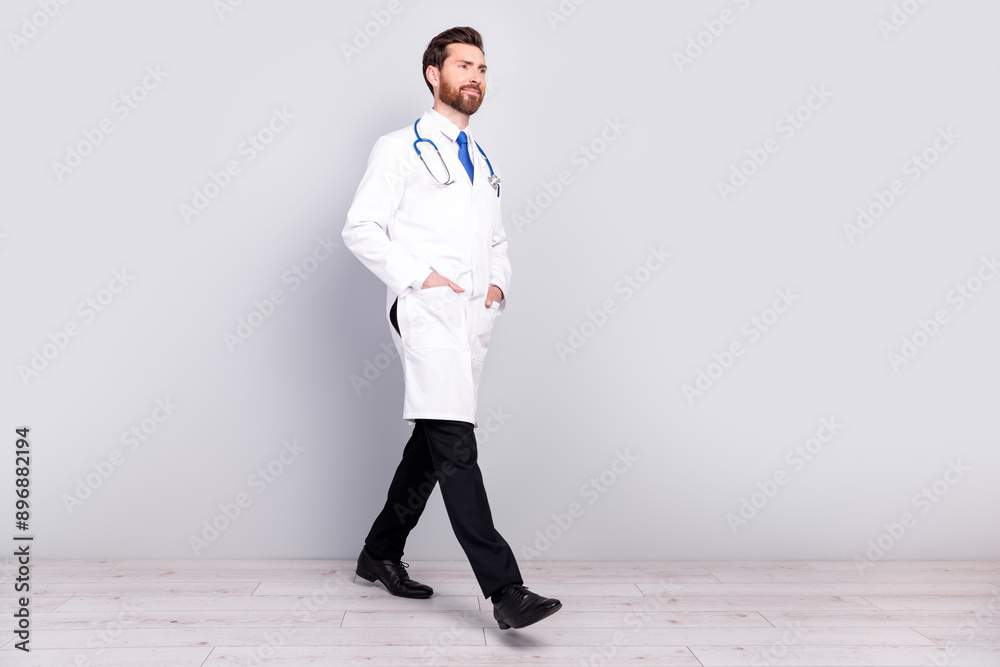 Full body profile portrait of experienced doctor walk empty space man wear white coat isolated on grey color wall background Full body profile portrait of experienced doctor walk empty space man wear white coat isolated on grey color wall background