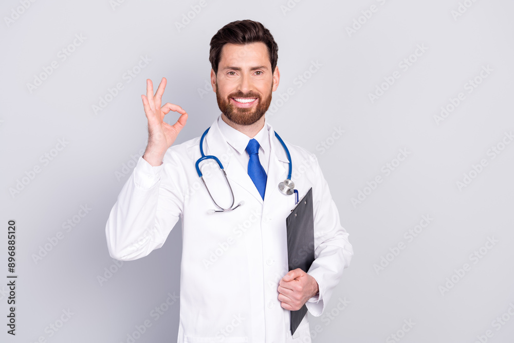 Photo of confident man doc qualified specialist wear uniform hold checklist okey sign isolated on grey color background