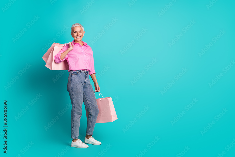 Full size photo of pretty aged woman store bags empty space wear shirt isolated on teal color background Full size photo of pretty aged woman store bags empty space wear shirt isolated on teal color background