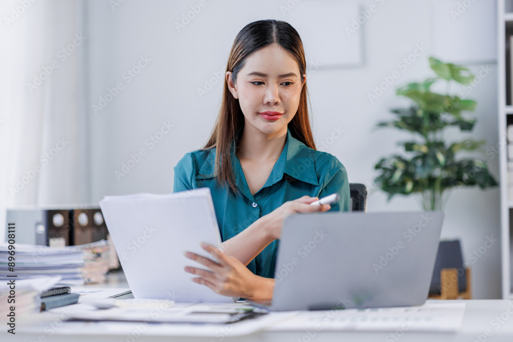Asian woman in the workplace Work Hard writing notes on a pad from her laptop computer with analytical charts and graphs in front of her, business people concept Asian woman in the workplace Work Hard writing notes on a pad from her laptop computer with analytical charts and graphs in front of her, business people concept