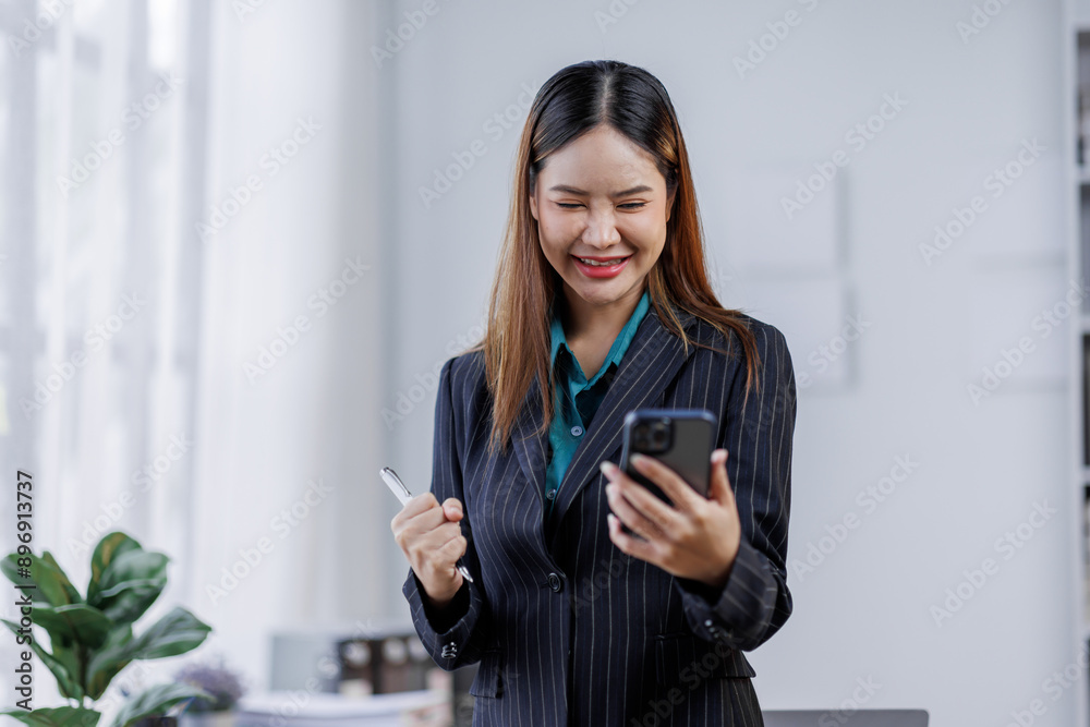 Young busy happy business asian woman employee, young female corporate executive holding digital phone standing at work. Young busy happy business asian woman employee, young female corporate executive holding digital phone standing at work.
