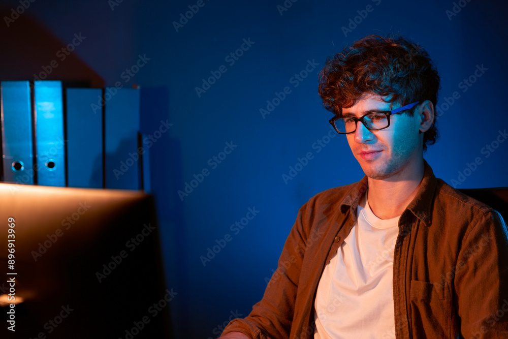 Young businessman concentrating on pc for creative startup project job at neon light modern office. Thinking marketing network online planning of creator to market channel design concept. Gusher. Young businessman concentrating on pc for creative startup project job at neon light modern office. Thinking marketing network online planning of creator to market channel design concept. Gusher.