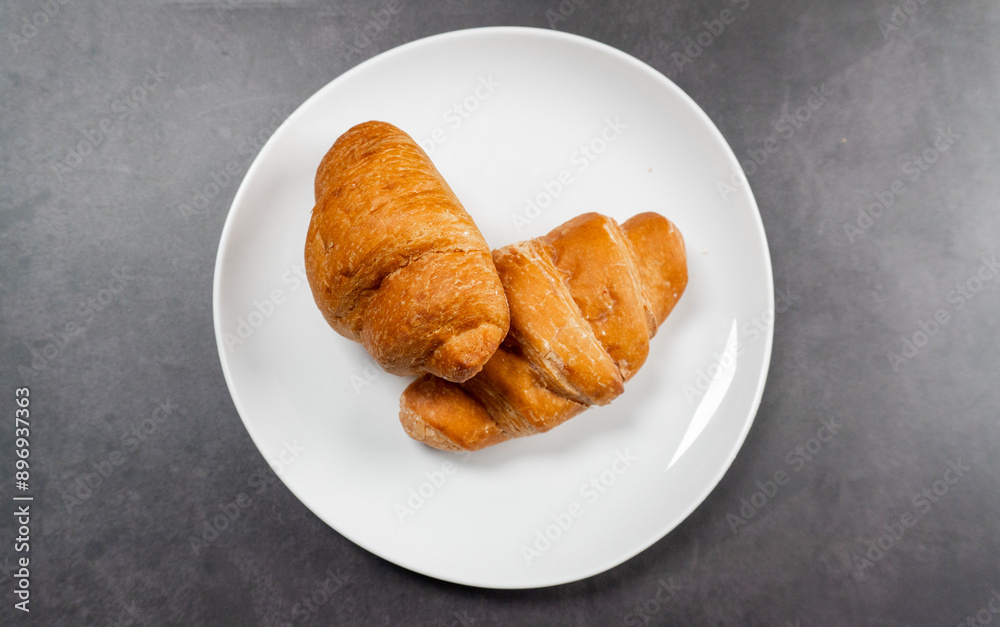 top view of pile of croissants in white plate on dark stone table top view of pile of croissants in white plate on dark stone table
