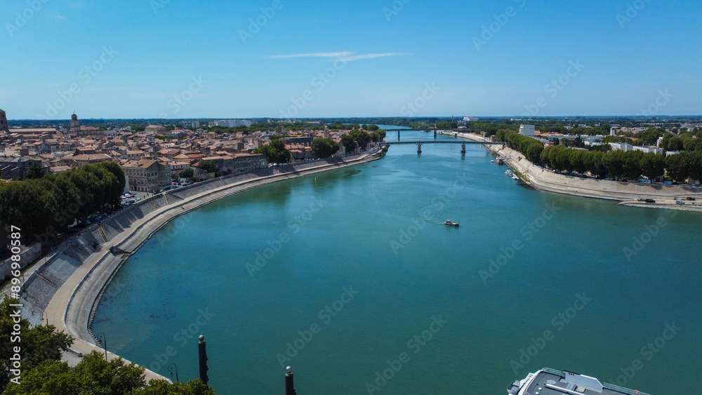 Rhone river passing through the city of Arles in Provence. Ferries and boats in the important river in Europe that flows into the Mediterranean. Towns along the river that attract tourists traveling. Rhone river passing through the city of Arles in Provence. Ferries and boats in the important river in Europe that flows into the Mediterranean. Towns along the river that attract tourists traveling.