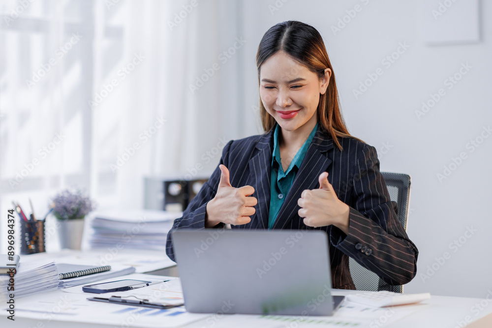 Charming Young happy asian business woman sitting on laptop computer in the office, asian employee business making report calculating balance Internal Revenue Service checking document. Charming Young happy asian business woman sitting on laptop computer in the office, asian employee business making report calculating balance Internal Revenue Service checking document.