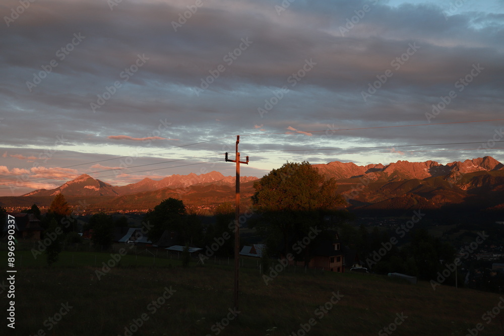Obraz premium Communication tower in the mountains. The mountain range is illuminated by sunlight. Romantic dinner at sunset with mountain views. Atmospheric panorama in the mountains.