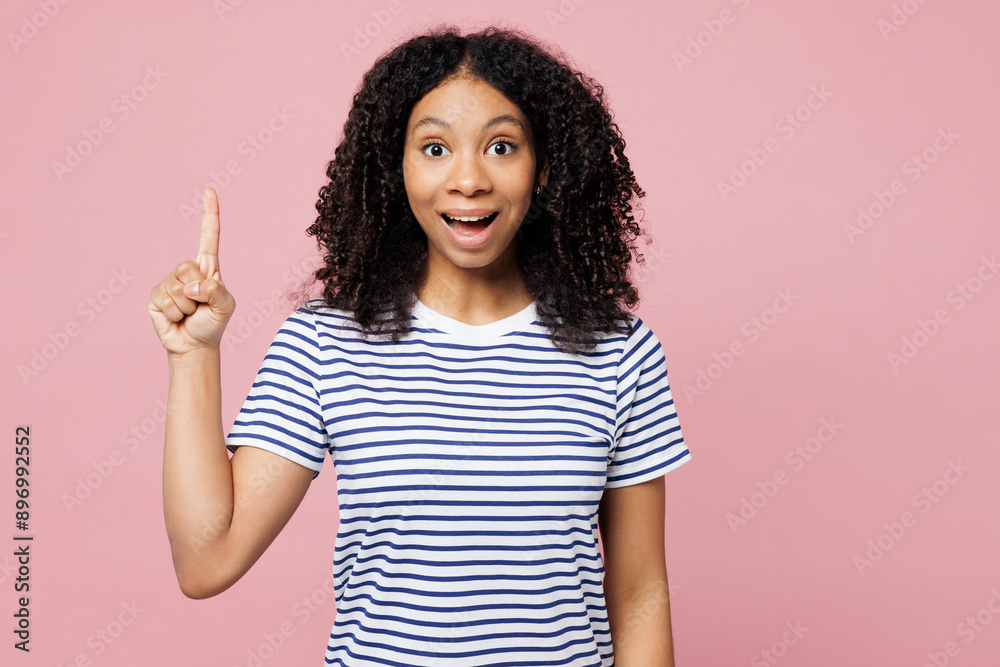 Little smart kid teen girl wears blue striped t-shirt casual clothes holding index finger up with great new idea isolated on plain pastel pink background studio portrait. Childhood lifestyle concept. Little smart kid teen girl wears blue striped t-shirt casual clothes holding index finger up with great new idea isolated on plain pastel pink background studio portrait. Childhood lifestyle concept.