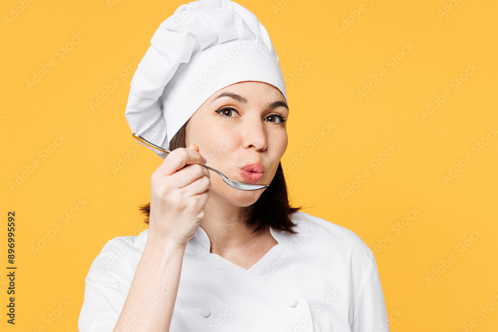 Close up young happy fun chef cook baker woman she wear white shirt black apron uniform toque chefs hat hold in hand spoon, taste dish isolated on plain yellow background studio. Cooking food concept. Close up young happy fun chef cook baker woman she wear white shirt black apron uniform toque chefs hat hold in hand spoon, taste dish isolated on plain yellow background studio. Cooking food concept.