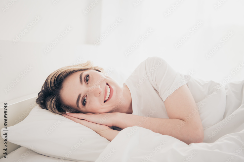 Photo of positive girl lying bed smiling in white interior indoors Photo of positive girl lying bed smiling in white interior indoors