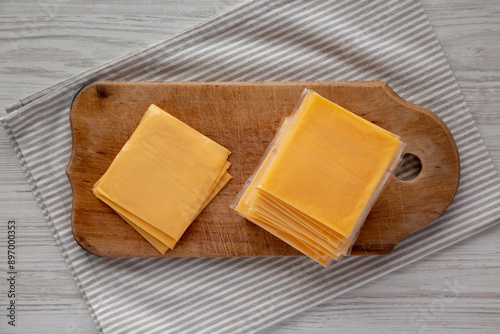 Yellow Cheddar American Cheese Stacked Slices on a wooden board, top view.