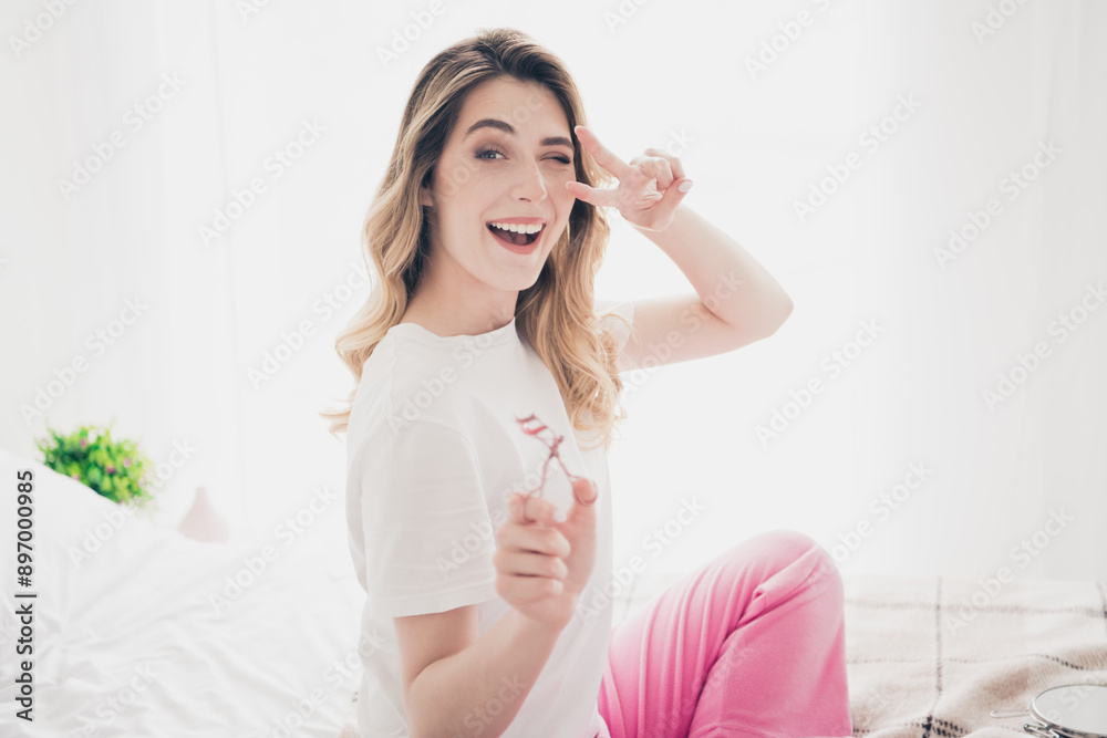 Photo of positive girl hold eye lashes curler make v sign room indoors Photo of positive girl hold eye lashes curler make v sign room indoors