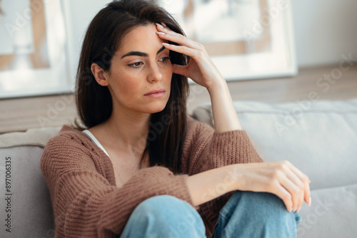 Depressed young woman thinking about her problems while sitting on the sofa at home Free Download Depressed young woman thinking about her problems while sitting on the sofa at home - GFXLoad