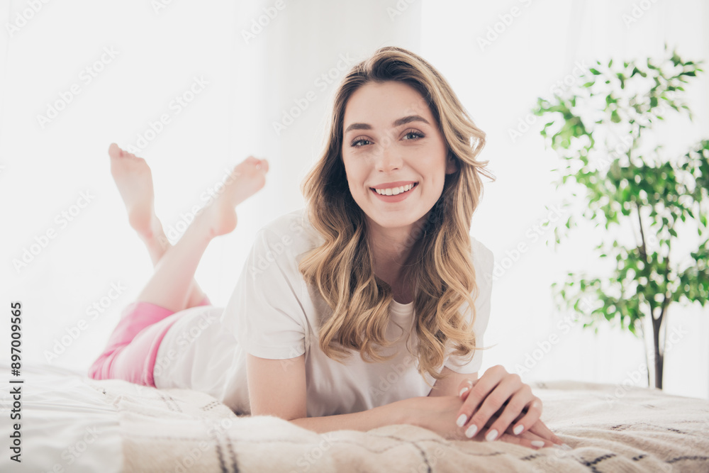 Photo of positive smiling girl lying bed resting in white apartment room interior Photo of positive smiling girl lying bed resting in white apartment room interior