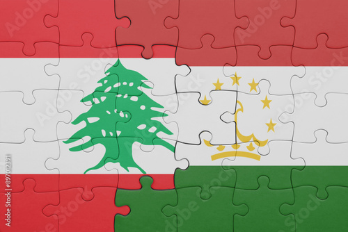 puzzle with the colourful national flag of lebanon and flag of tajikistan . photo