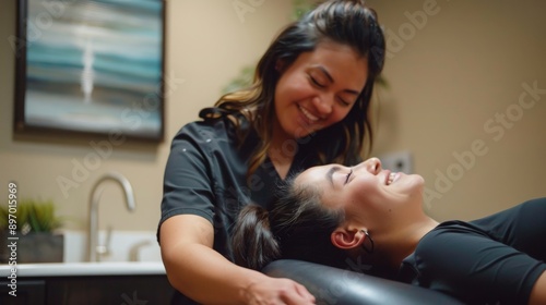 A woman relaxes while receiving a facial treatment from a smiling esthetician in a spa setting.