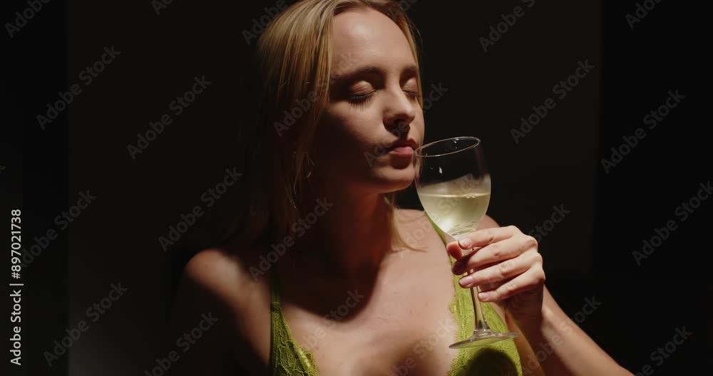 Cinematic view of a beautiful girl dressed in sexy lingerie taking a sip of delicious white wine Cinematic view of a beautiful girl dressed in sexy lingerie taking a sip of delicious white wine