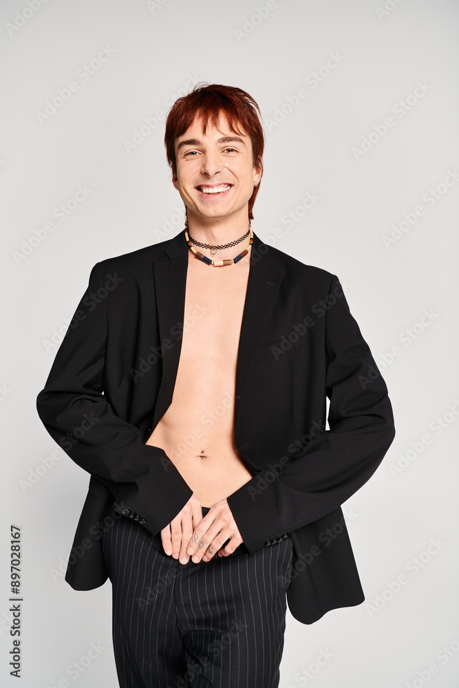 A stylish young man in a suit poses confidently for a photo against a grey studio background. A stylish young man in a suit poses confidently for a photo against a grey studio background.