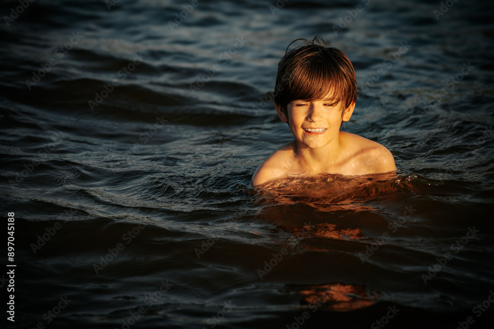 A boy swimming in the ocean, smiling and flashing a peace sign with his fingers. The image captures a joyful and carefree moment during a summer day at the beach A boy swimming in the ocean, smiling and flashing a peace sign with his fingers. The image captures a joyful and carefree moment during a summer day at the beach