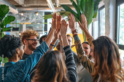 Group of diverse young professionals giving high fives in a modern office photo