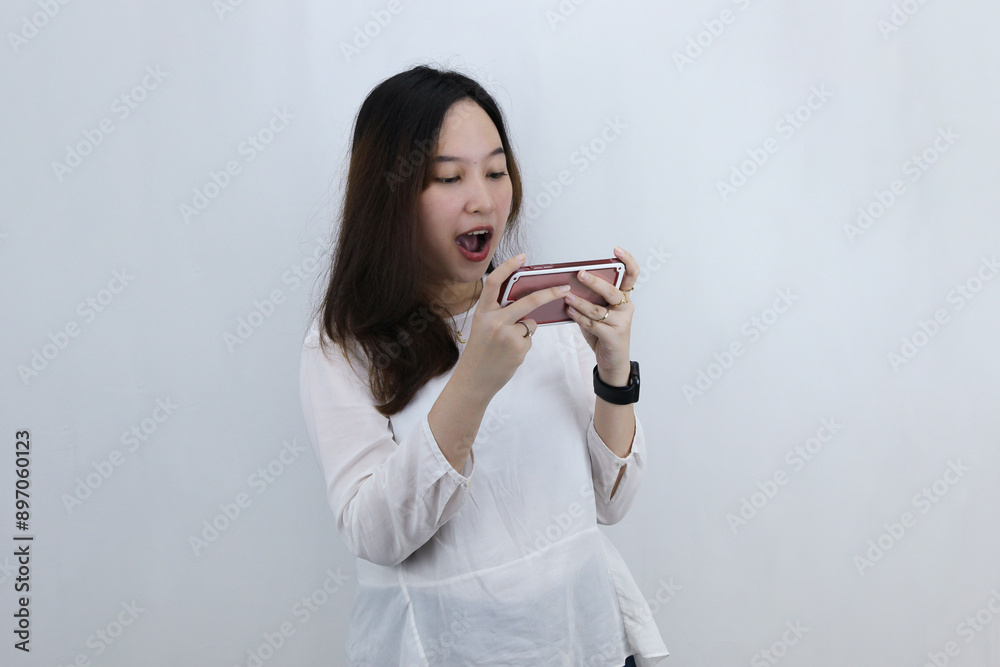 Excited Young Asian woman playing online game on smart phone Excited Young Asian woman playing online game on smart phone