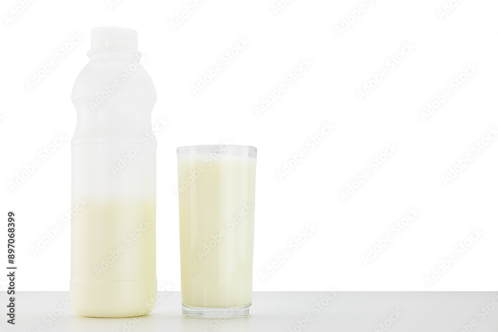 Glass of fresh milk and bottle of milk on white table on white background Glass of fresh milk and bottle of milk on white table on white background